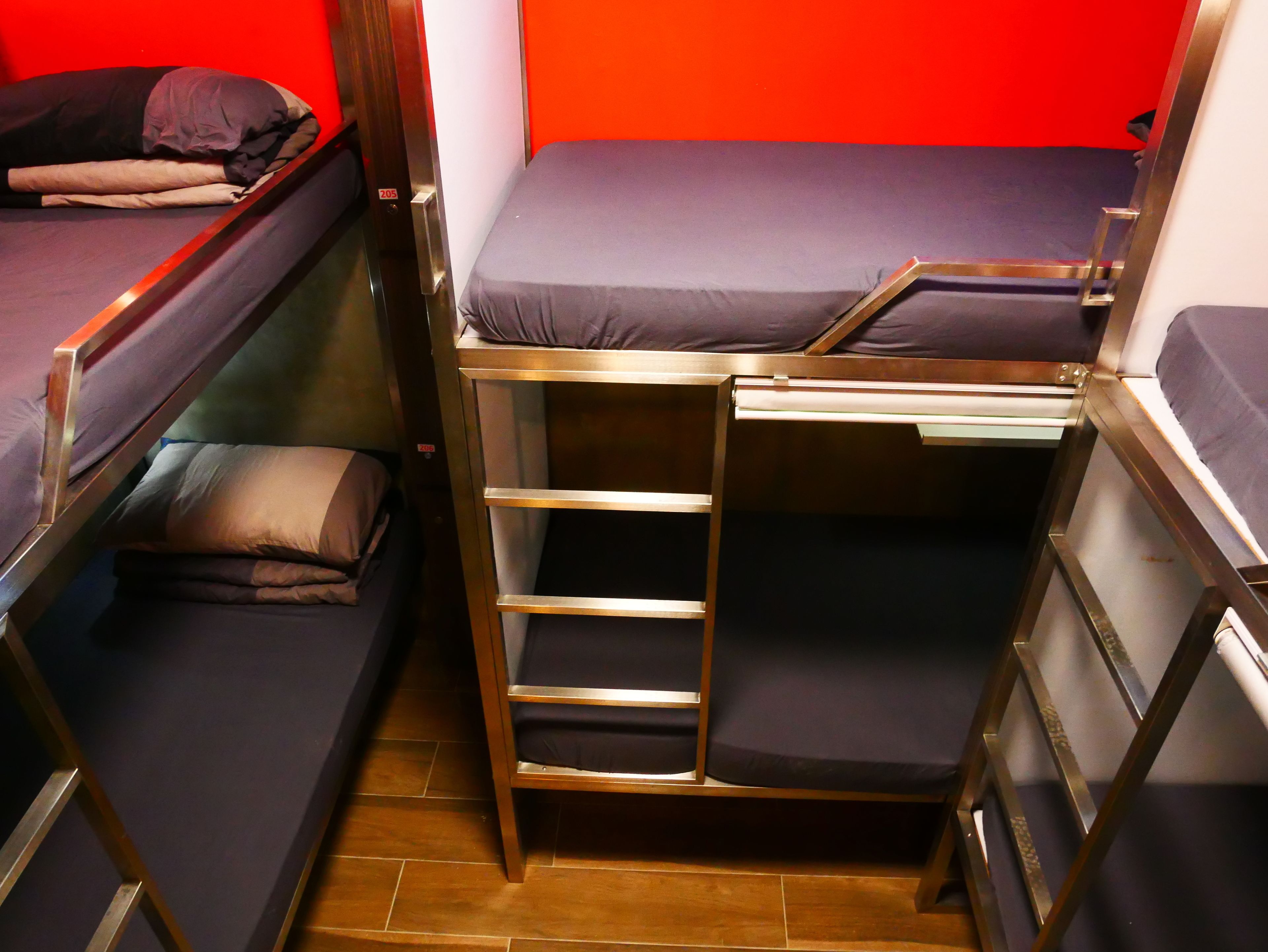 Una habitación pequeña con literas, una escalera y pared roja.