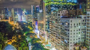 A cityscape at night with modern buildings, a prominent dome structure, and a busy street with palm trees. - Urban Pack - Hostel (Kowloon)