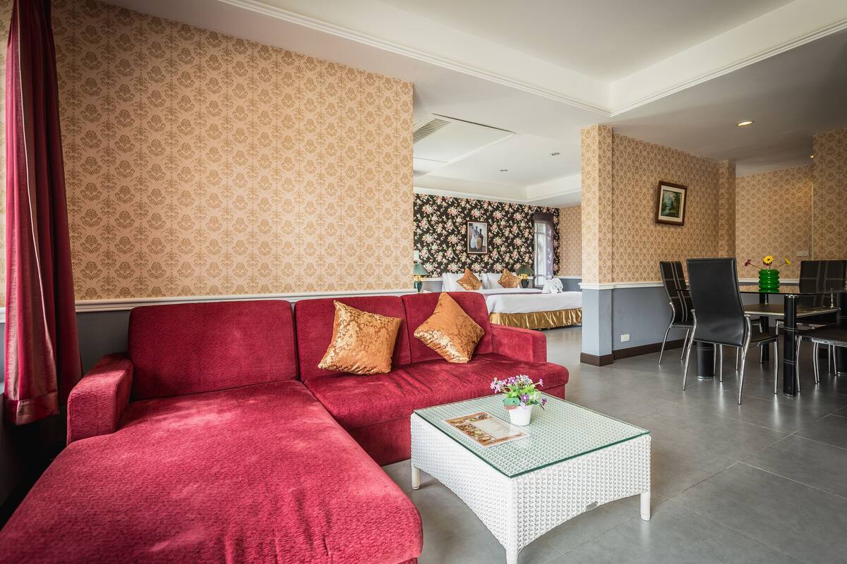Una sala de estar con un sofá rojo, una mesa de centro de vidrio y un comedor con sillas y una mesa.