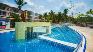 Una piscina con fuente, rodeada de palmeras y edificios.