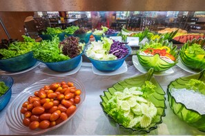 A buffet with various salads and vegetables displayed in bowls.