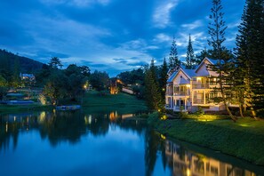 A lakeside property with a large house featuring multiple balconies and a well-maintained lawn. - Brookside Valley Resort (Rayong)