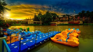 Un muelle con coloridos barcos pedales, un puente y un edificio con balcón con vistas al agua.