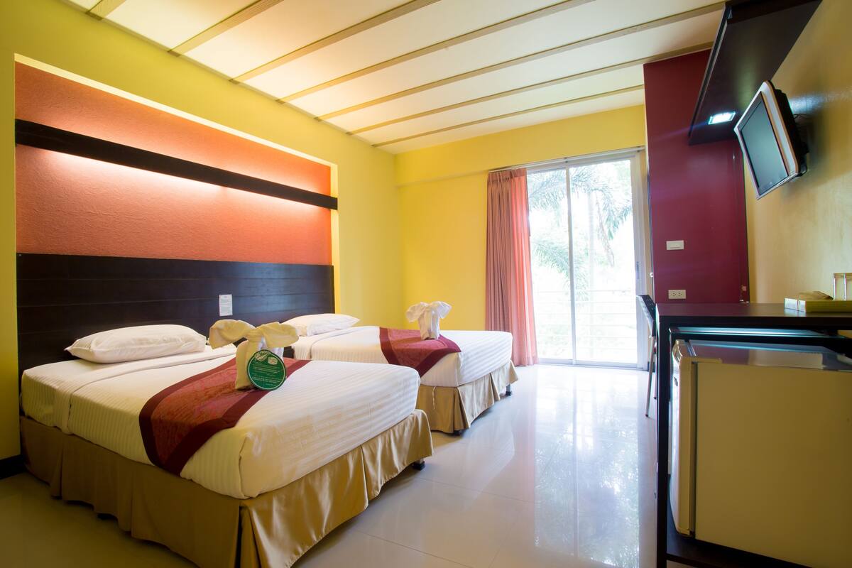 Una habitación de hotel con dos camas, televisión y refrigerador.