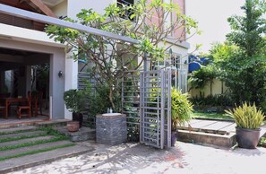 A residential entrance with a gated patio, potted plants, and a small outdoor seating area. - Neakru Guesthouse and Restaurant (Kampot)