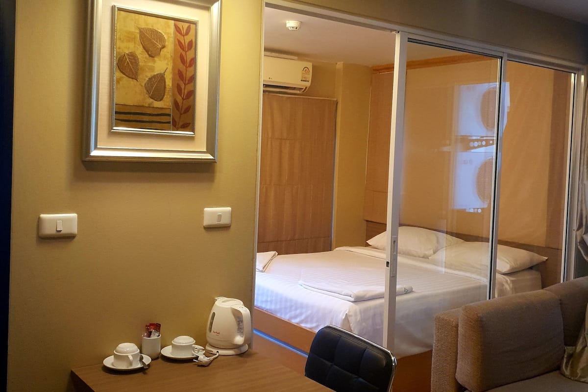 A hotel room with a bed, a desk with a chair, a framed picture, and a coffee maker.