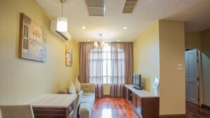 Un espacio habitable compacto con comedor, sofá, televisor y kitchenette.