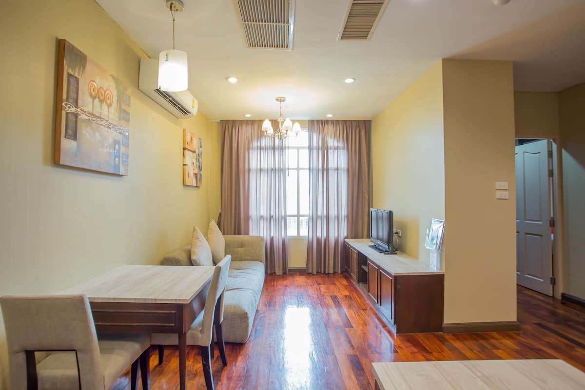 A compact living space with a dining area, sofa, TV, and kitchenette.