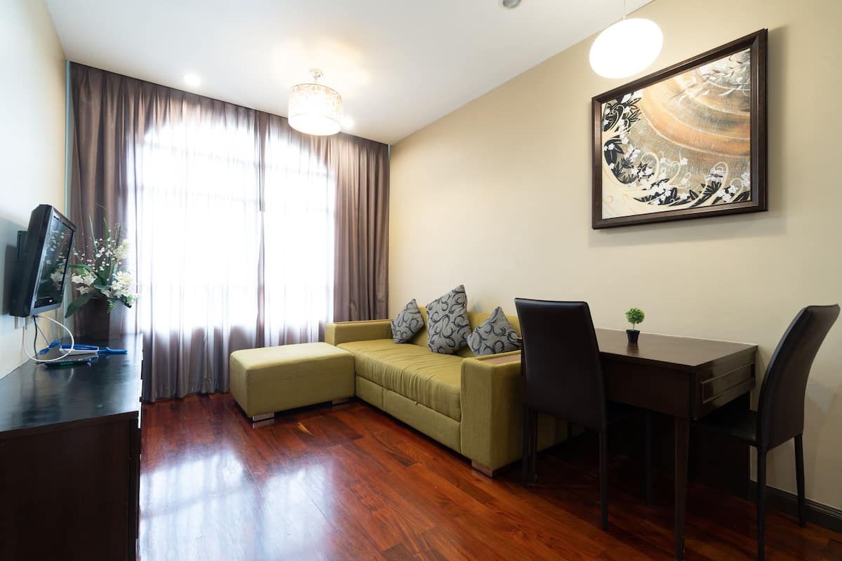 A living room with a sofa, a dining table with chairs, a TV, and a painting on the wall.