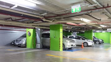 A multi-level parking garage with green pillars, clear directional signage, and a clean, well-maintained floor.