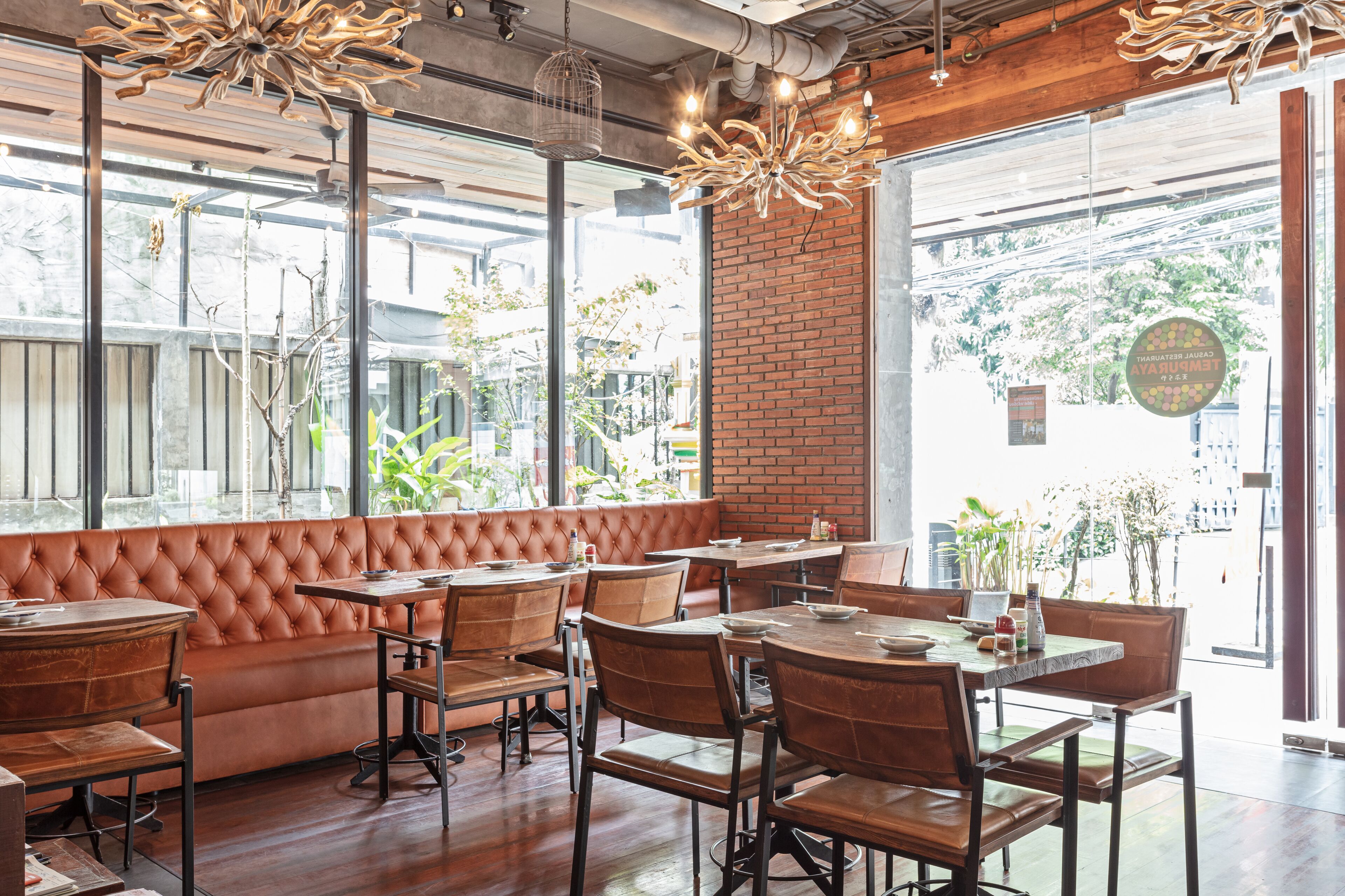 Un interior de restaurante con área de asientos en cuero, mesas y sillas de madera.