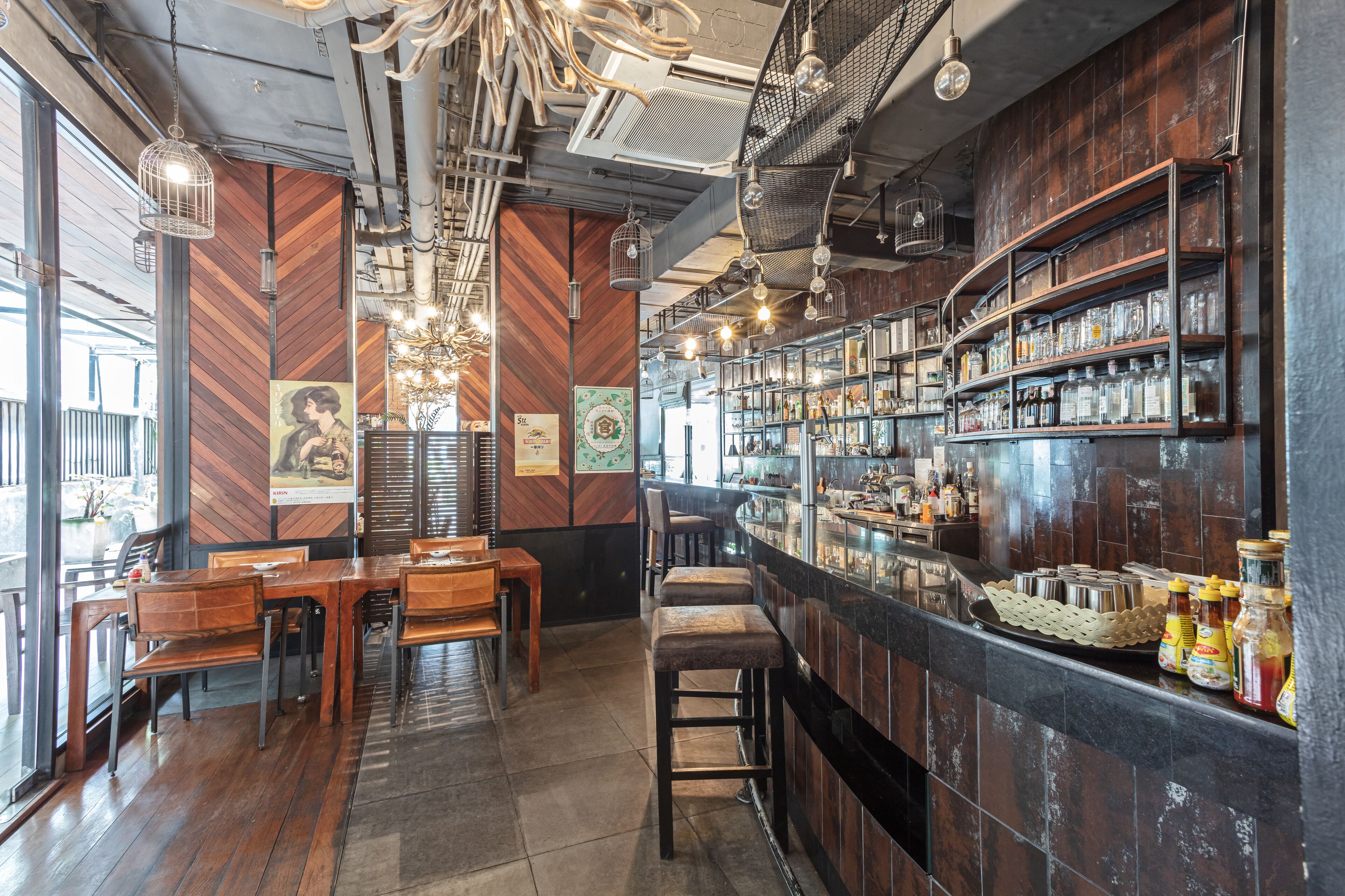 Un espace bar avec des meubles en bois, des luminaires suspendus et des étagères remplies de bouteilles.