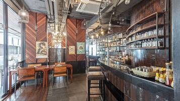 Un espace bar avec des meubles en bois, des luminaires suspendus et des étagères remplies de bouteilles.