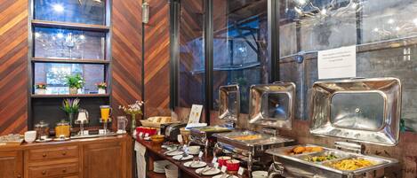 A buffet setup with multiple food stations and a wooden counter with various dishes and utensils.