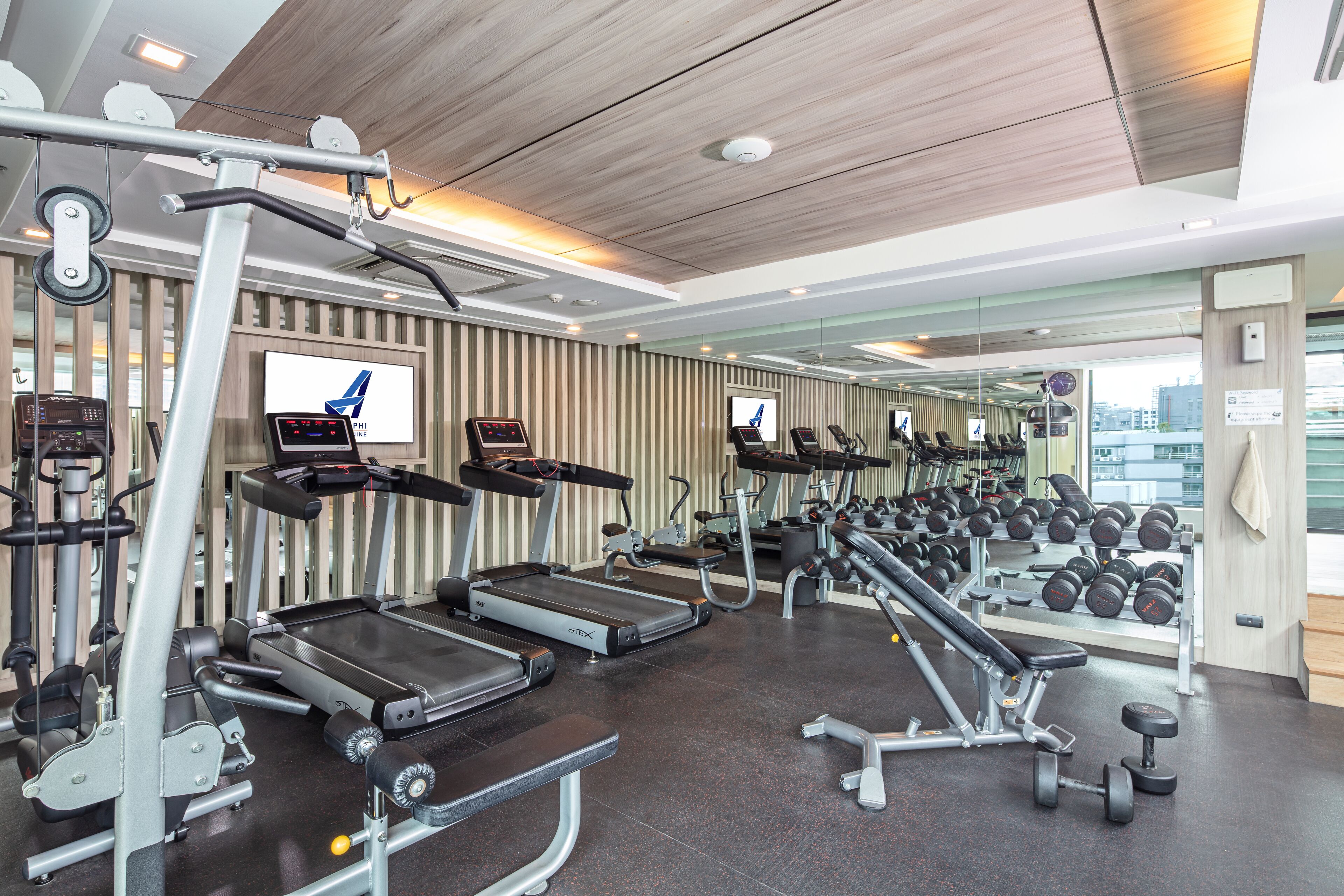 A modern gym with treadmills, weight machines, and a mirrored wall.