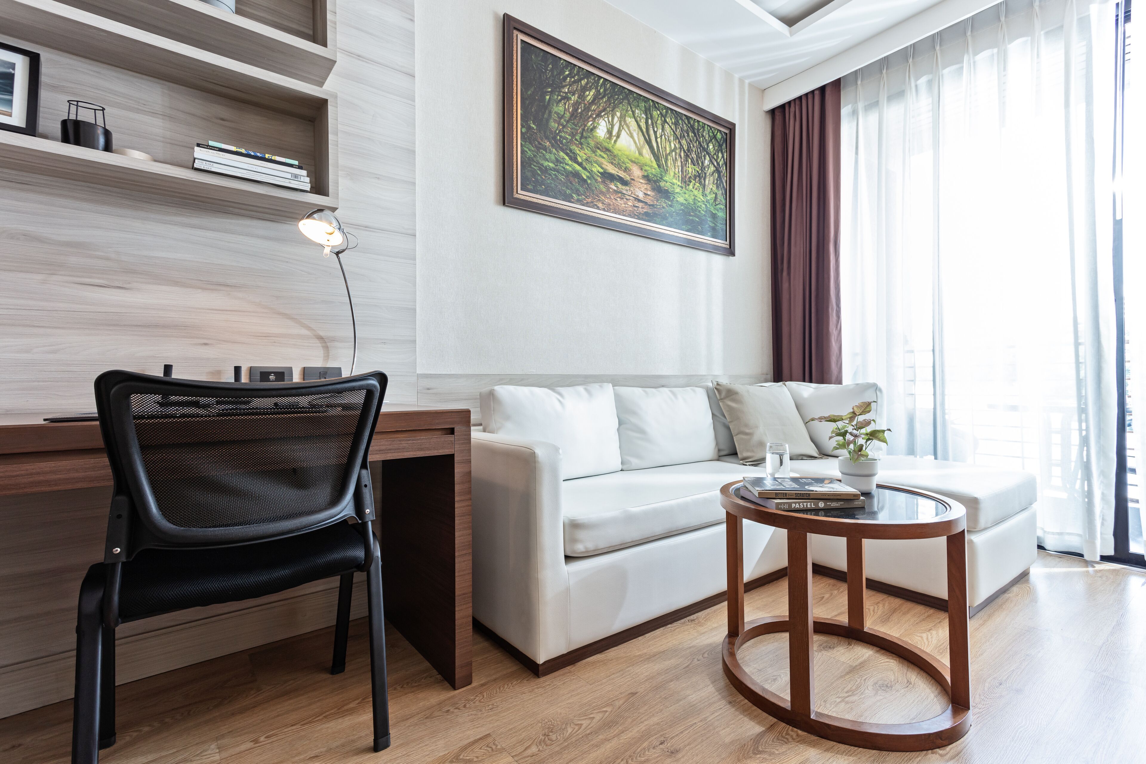 Una sala de estar moderna con un sofá blanco, una silla negra, una mesa de centro de madera y un cuadro en la pared.