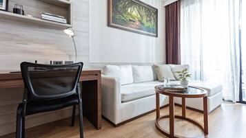 A modern living room with a white sofa, a black chair, a wooden coffee table, and a painting on the wall.