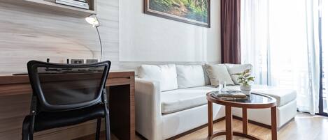 Una sala de estar moderna con un sofá blanco, una silla negra, una mesa de centro de madera y un cuadro en la pared.