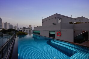 Una piscina al aire libre, sombrillas, sillones reclinables de piscina