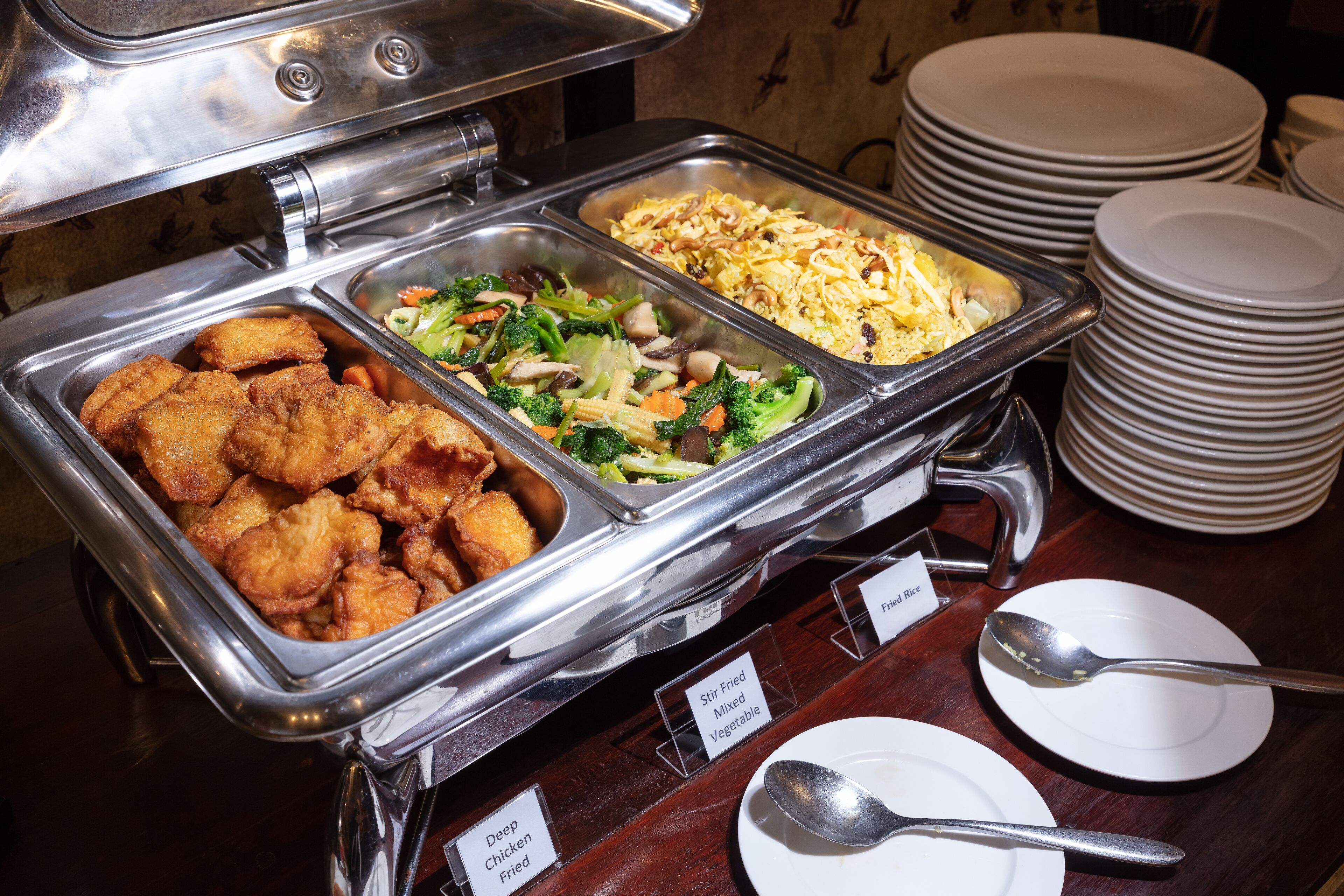 A buffet with labeled food options including deep fried chicken, stir fried mixed vegetables, and fried rice.