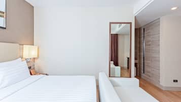 Een moderne hotelkamer met een groot bed, een nachtkastje met lamp, een spiegel en een kledingkast met schuifdeuren.