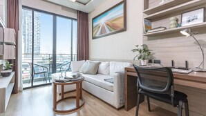 Een moderne woonkamer met een bank, een bureau, een stoel, een ronde tafel en een potplant.