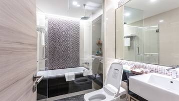 Un baño moderno con cabina de ducha de vidrio, un inodoro blanco y un espejo grande sobre el lavamanos.