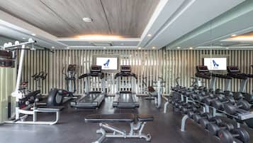 A gym with treadmills, elliptical machines, weight benches, and dumbbells.