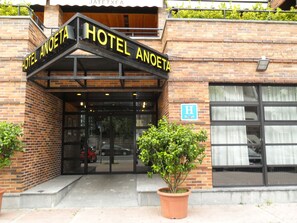 The entrance to Hotel Anoeta with a brick facade, a signboard, and a potted plant in front. - Hotel Anoeta (San Sebastián)