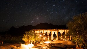 Una escena nocturna con cielo estrellado, piscina y un edificio con arcos.