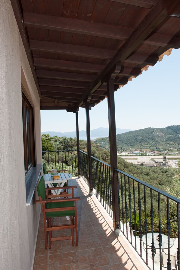Un balcón con una mesa y sillas, con vista a un paisaje montañoso.