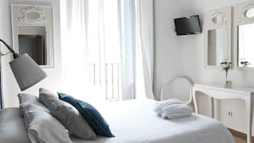 Un dormitorio con cama, lámpara de noche, televisor, escritorio y ventana con cortinas.