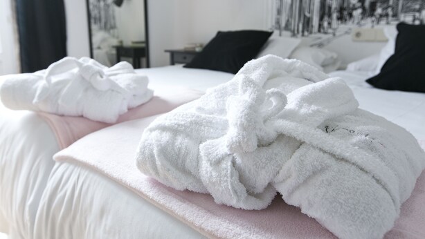 Una cama bien hecha con toallas blancas y un edredón rosa.