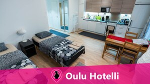Una habitación de hotel moderna con cama, mesitas de noche, escritorio y kitchenette.