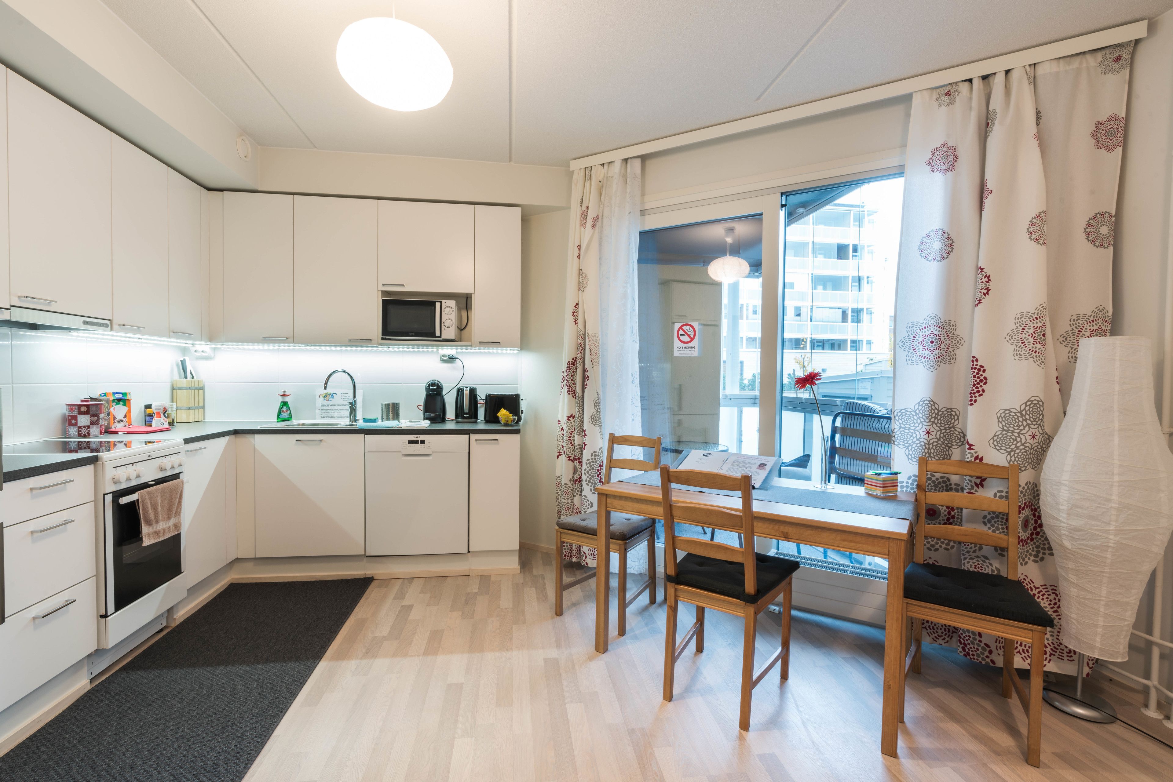 Une cuisine compacte avec des meubles blancs, un four à micro-ondes et un coin repas comprenant une table et des chaises.