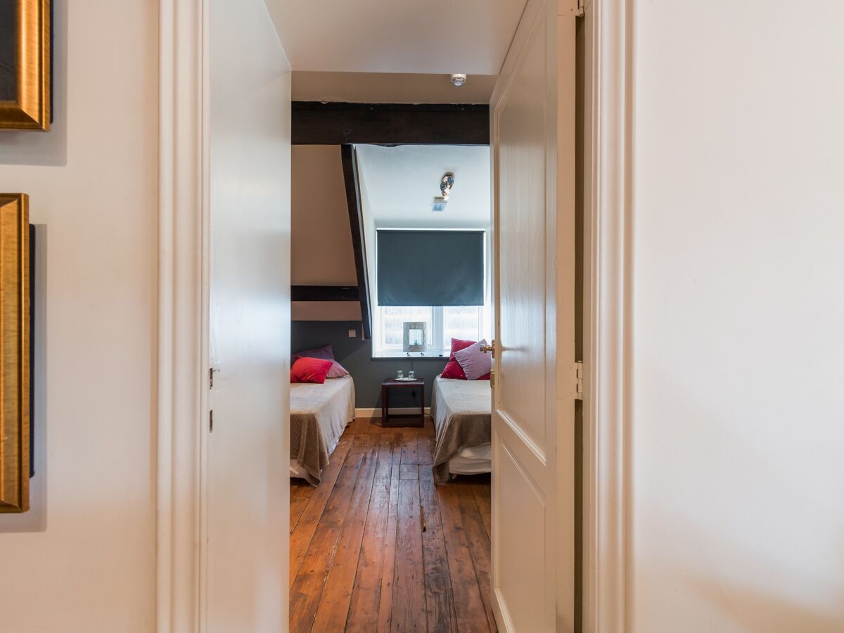 Un pasillo estrecho que conduce a un dormitorio con dos camas, una mesita y una ventana con vistas.