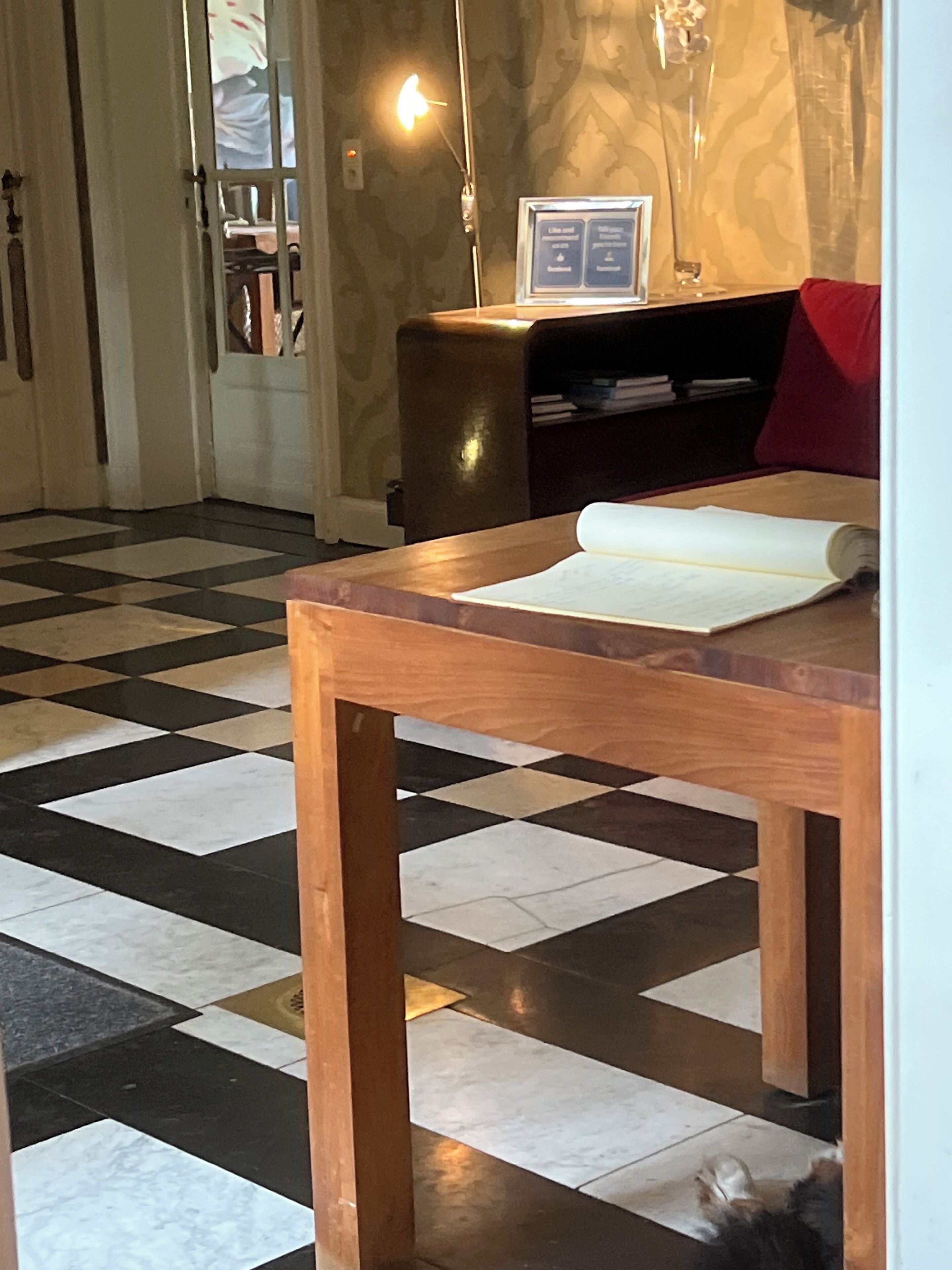 A wooden table with a rolled-up document, a patterned floor, and a lamp in the background.