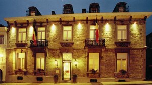 A stone building with multiple balconies, each with a small railing and potted plants. - Hotel Dufays (Stavelot)