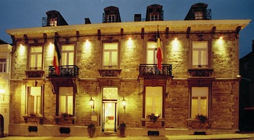 Un edificio de piedra con varios balcones, cada uno con barandilla y macetas.