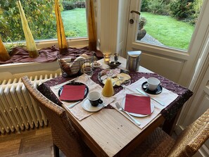 Una mesa de comedor lista con platos, cubiertos, servilletas, vasos y una cesta de pan.
