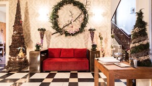 A checkered floor, a red sofa, a wooden table, a Christmas tree, and a wreath on the wall. - Hotel Dufays (Stavelot)