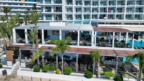Un hotel moderno con varios pisos, zonas de estar al aire libre y una piscina.