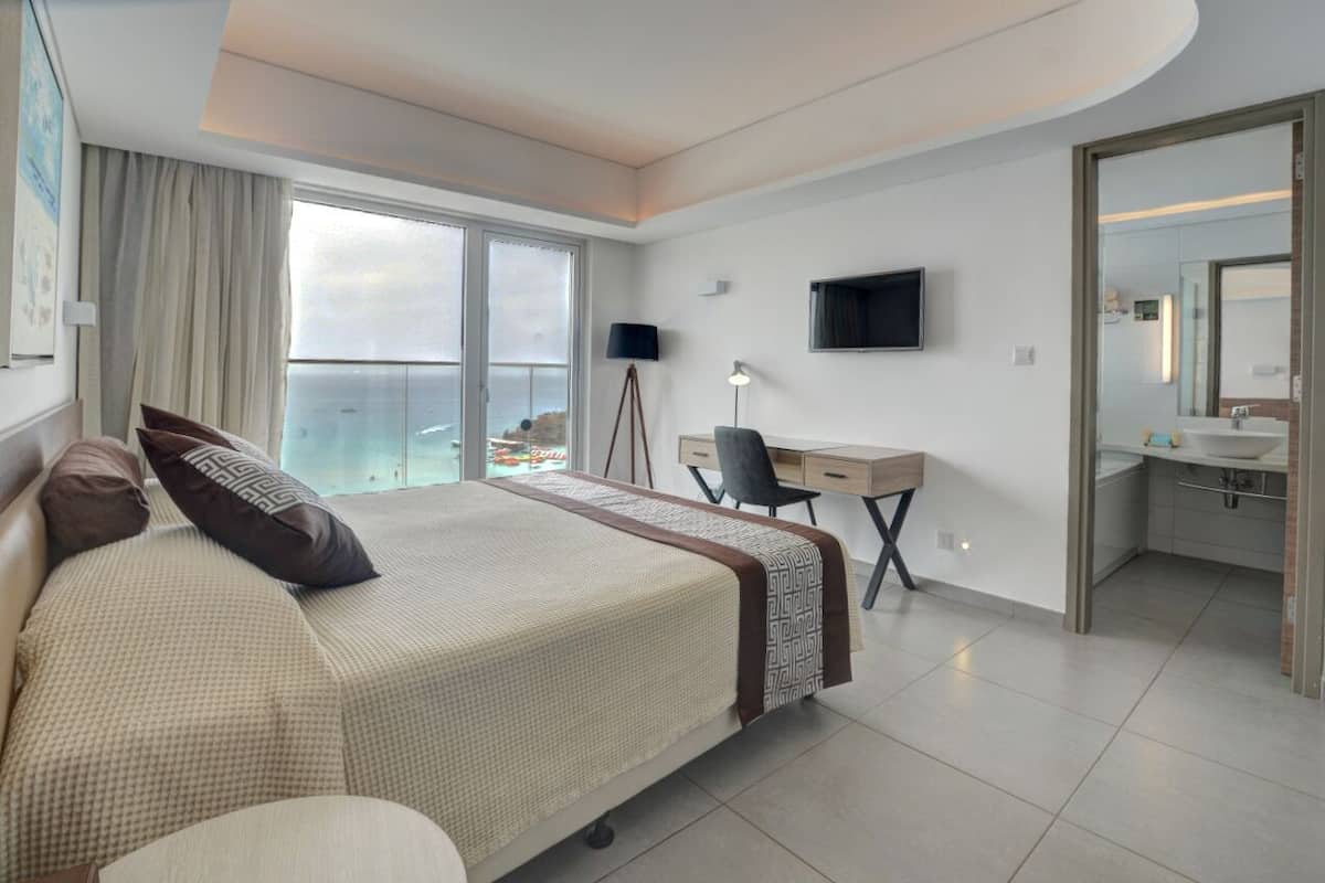 Een moderne hotelkamer met een groot bed, een bureau, een stoel, een televisie en een balkon met uitzicht.