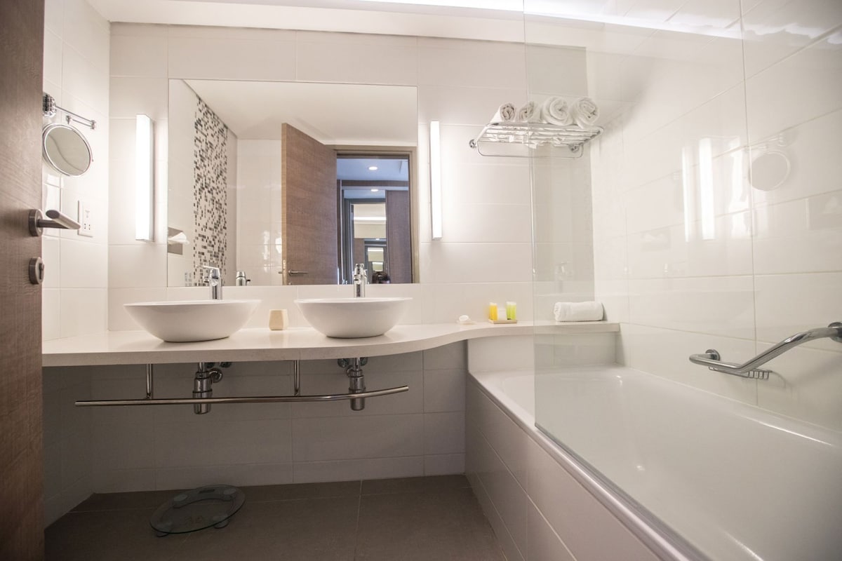 Une salle de bain moderne avec deux lavabos, une grande baignoire et une douche.