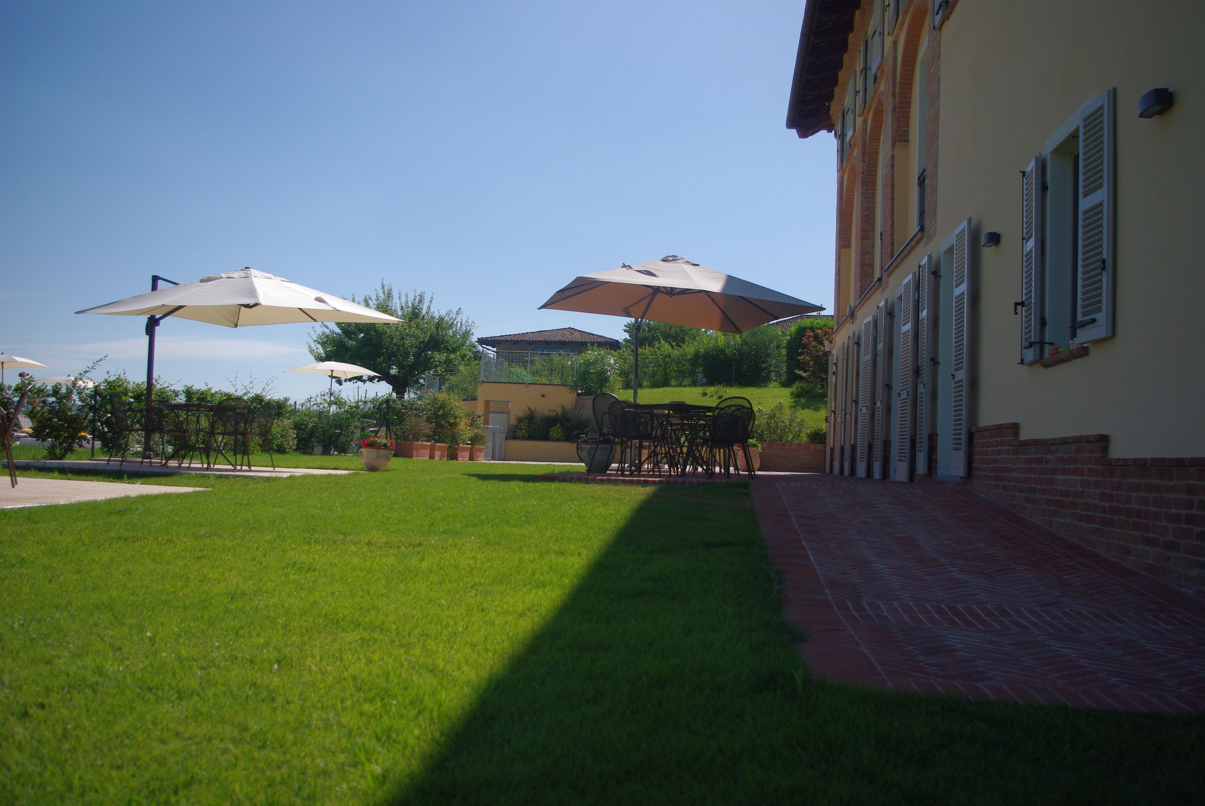 A courtyard with a lawn, outdoor furniture, and umbrellas.