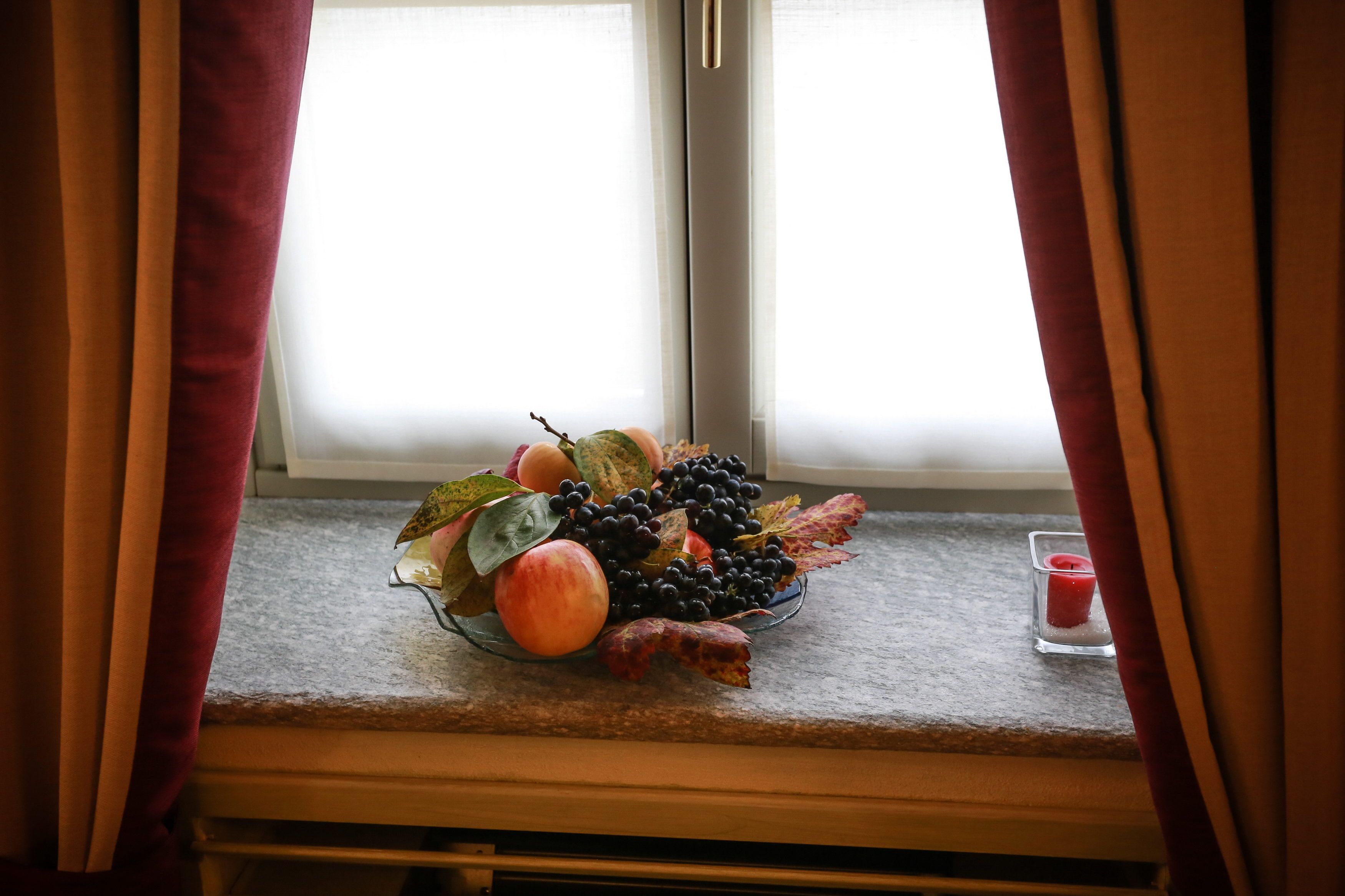 Un frutero en el alféizar de una ventana con una vela.