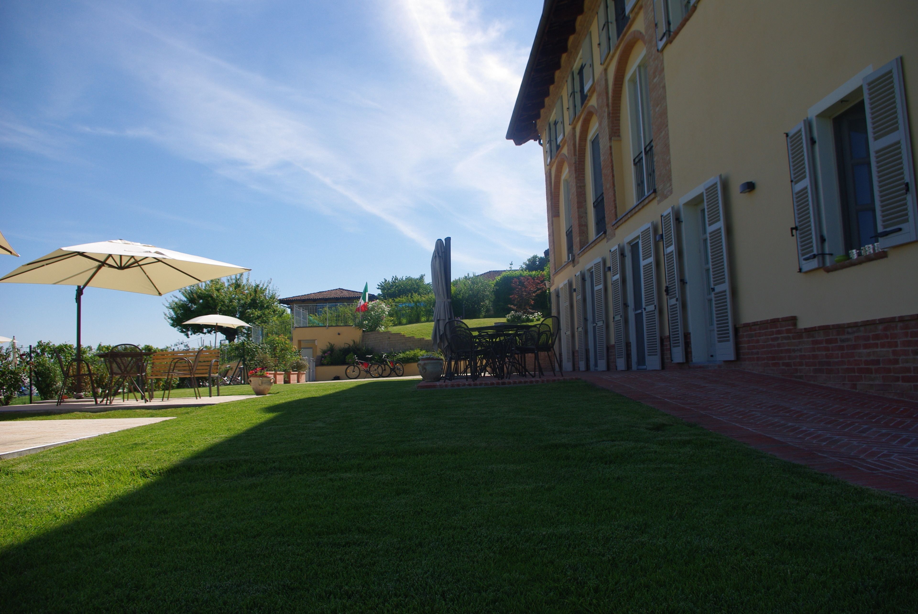 A courtyard with a lawn, outdoor seating, and a building with shutters.