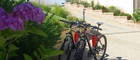Una bicicleta estacionada en un camino de grava, con una casa al fondo.