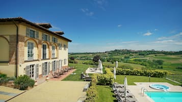 A hotel with a pool, outdoor seating, and a view of the countryside.