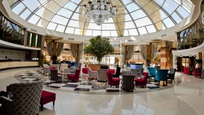 A spacious lobby with a high glass ceiling, a central tree, and multiple seating areas. - Side Alegria Hotel & Spa - Adults Only - All inclusive (Manavgat)